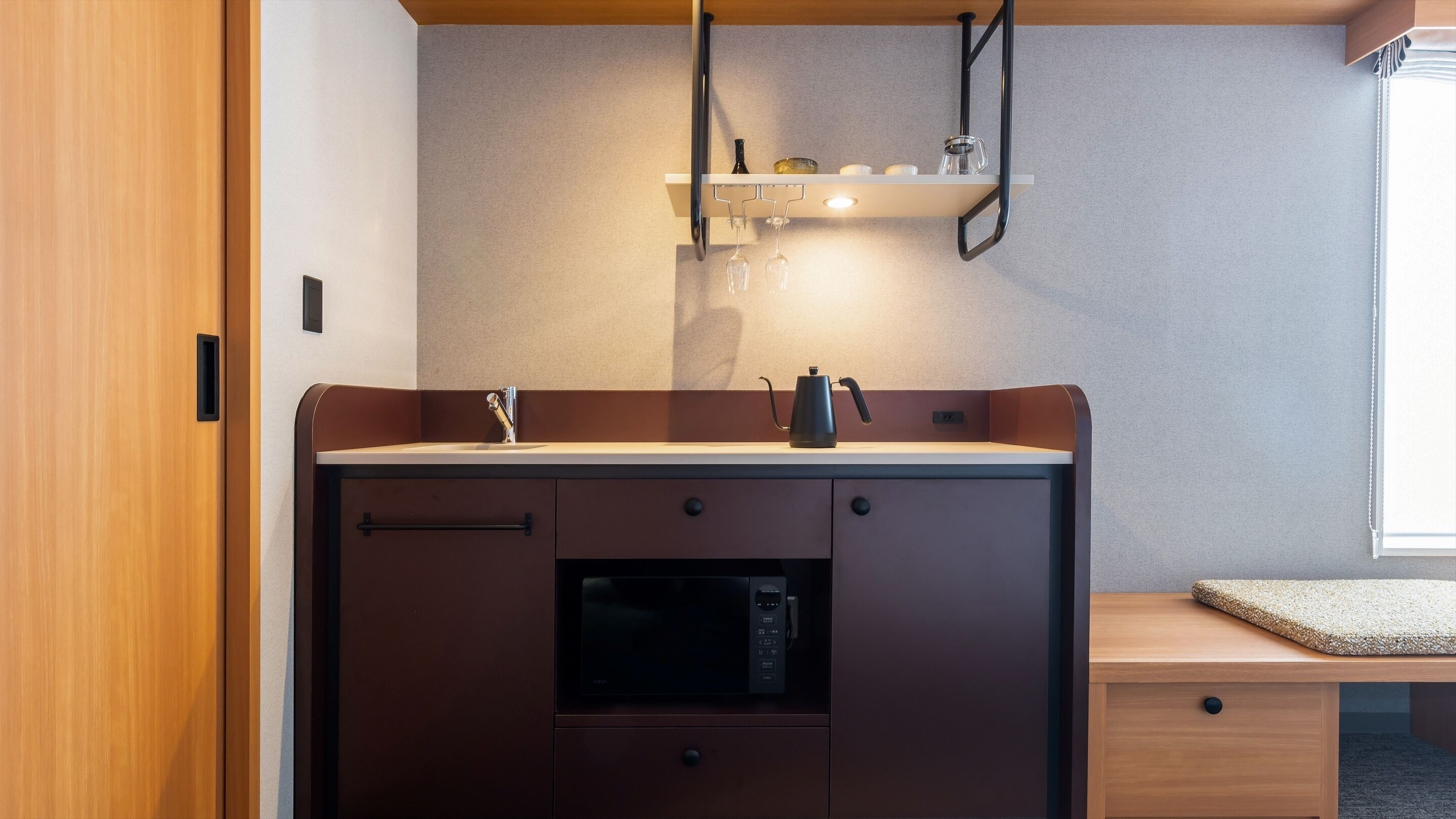 Un angolo cottura compatto con forno, lavello e macchina da caffè.