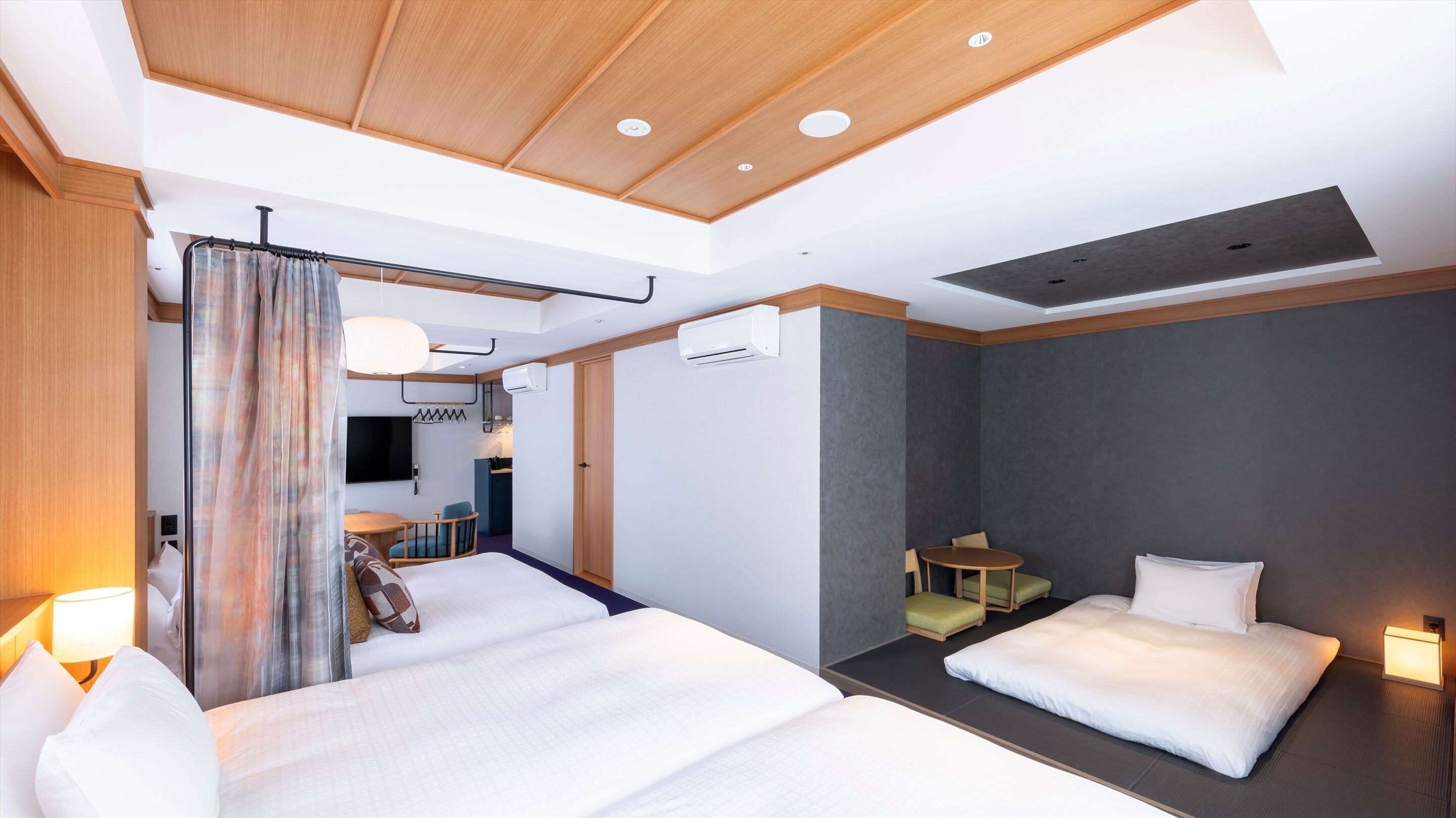 Une chambre d’hôtel avec deux lits, un bureau, une chaise, une télévision et un appareil de climatisation.