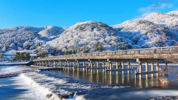 Un puente de madera sobre un río, con colinas nevadas al fondo.
