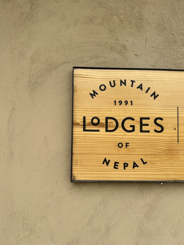Une enseigne en bois portant l’inscription « MOUNTAIN LODGES OF NEPAL 1991 ».