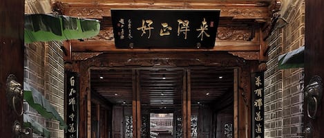A traditional Chinese architectural entrance with a tiled roof, wooden beams, and a signboard.
