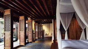Une chambre traditionnelle avec un lit, des piliers en bois et un baldaquin.