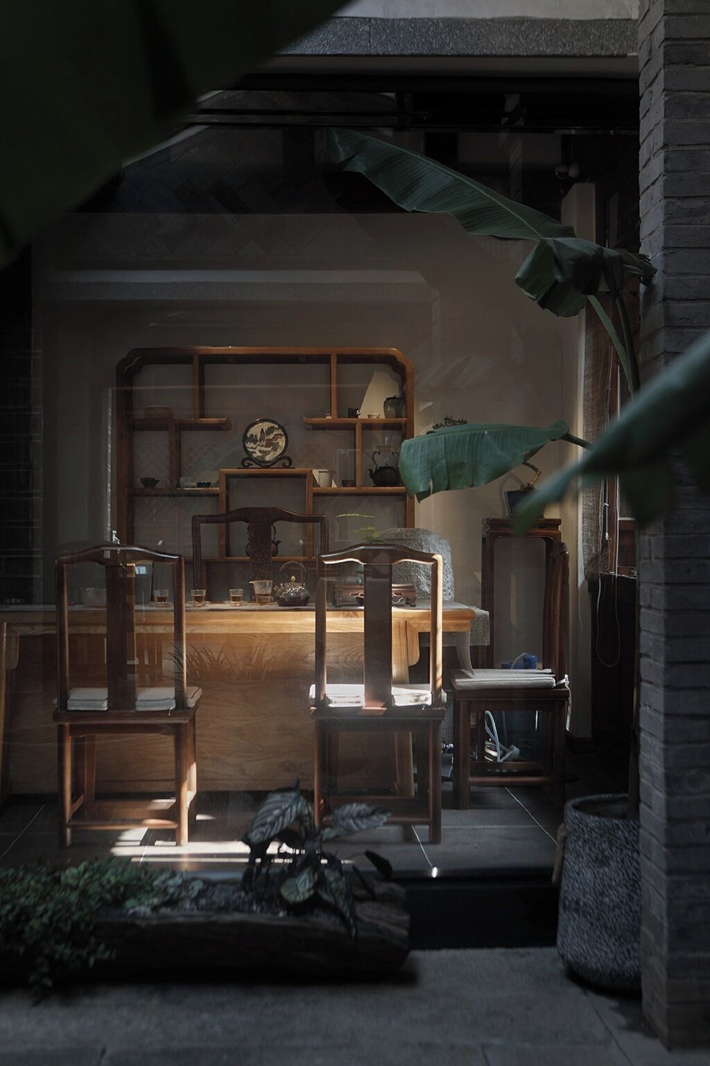A cozy room with a wooden desk, chairs, and shelves with various items.