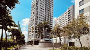 A modern urban street with a paved walkway, tall residential buildings, and trees.