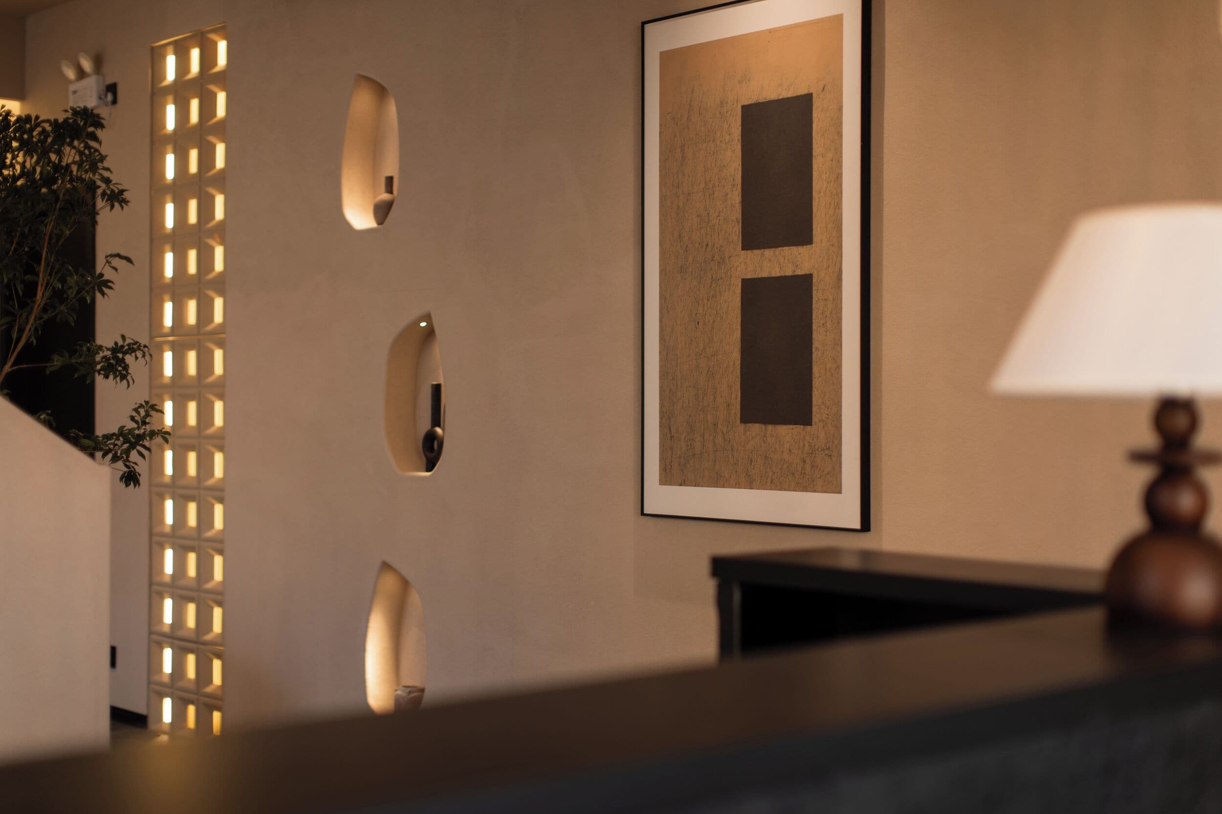 A modern interior with a reception desk, a framed artwork on the wall, and a decorative wall panel.