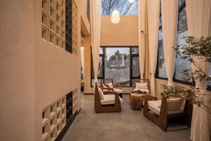 A modern interior with a long corridor, wooden chairs, a small table, and large windows.