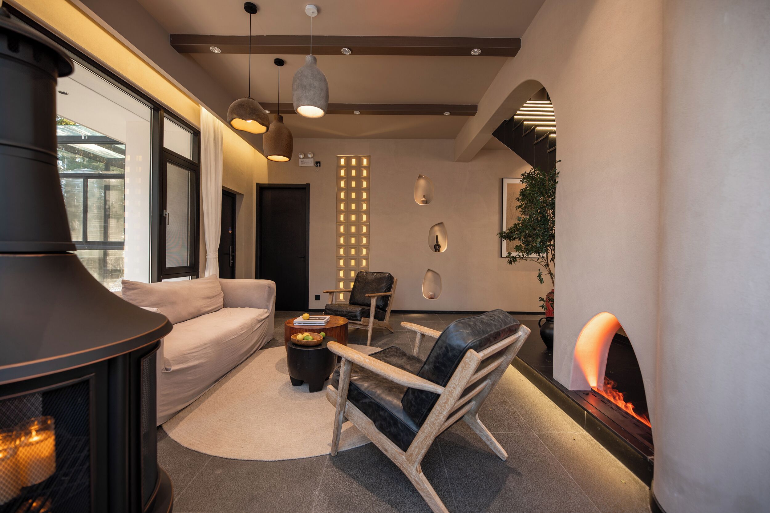 Una sala moderna con chimenea, un sofá, una mesa de centro y un sillón de cuero.