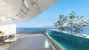 A modern outdoor terrace with a glass infinity pool, a seating area, and a view of the ocean. - Anyu Aranya Collection Sea View Resort Hotel (Dali)
