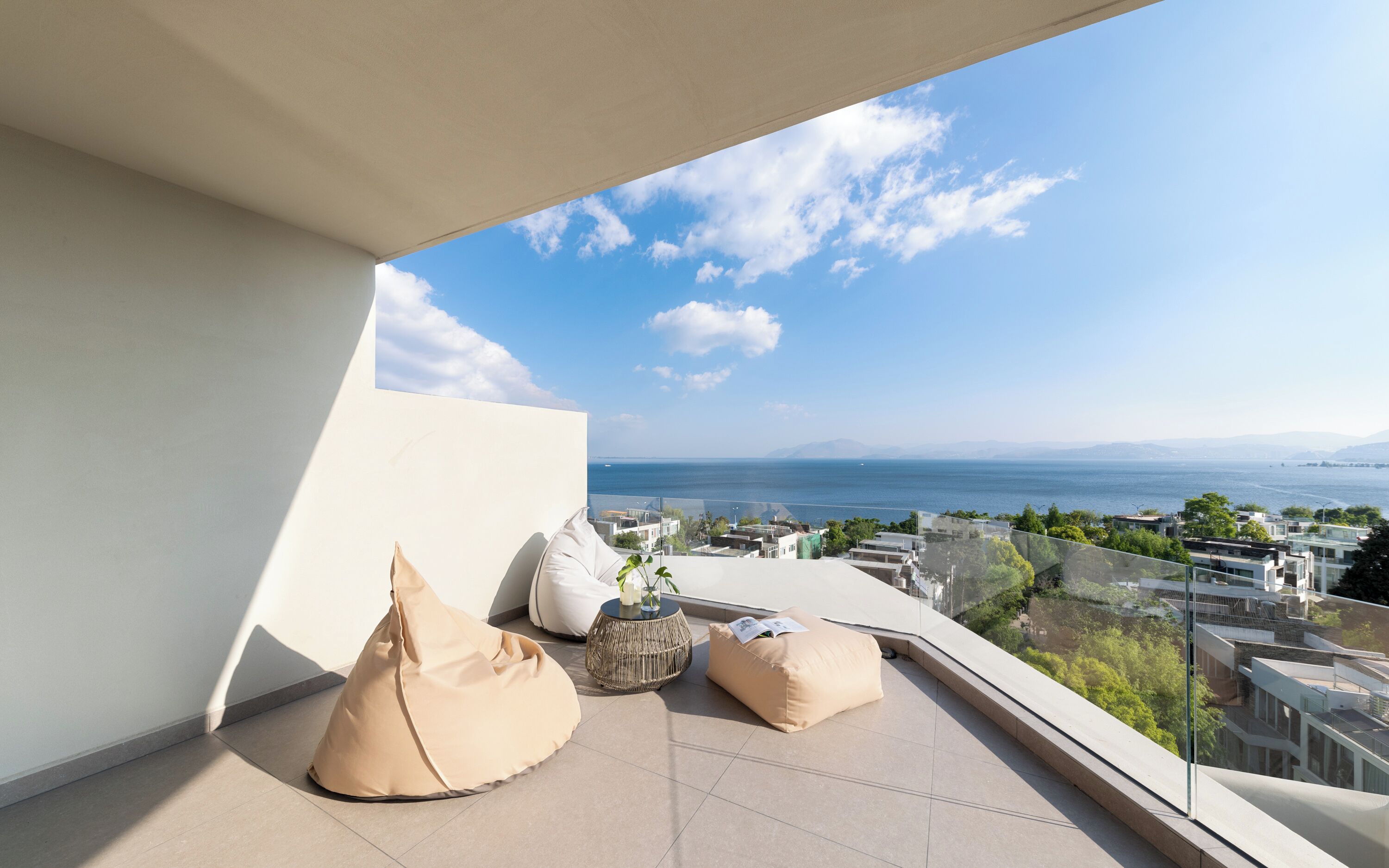 Un balcón con vistas al mar y al paisaje urbano, que incluye un sillón de exterior, una mesa redonda y un cojín.