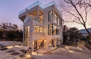 Una casa moderna de dos pisos con amplios ventanales, un balcón y un interior luminoso.