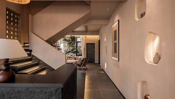 Un interior moderno con una escalera, una recepción y un pasillo que conduce a una zona de estar.