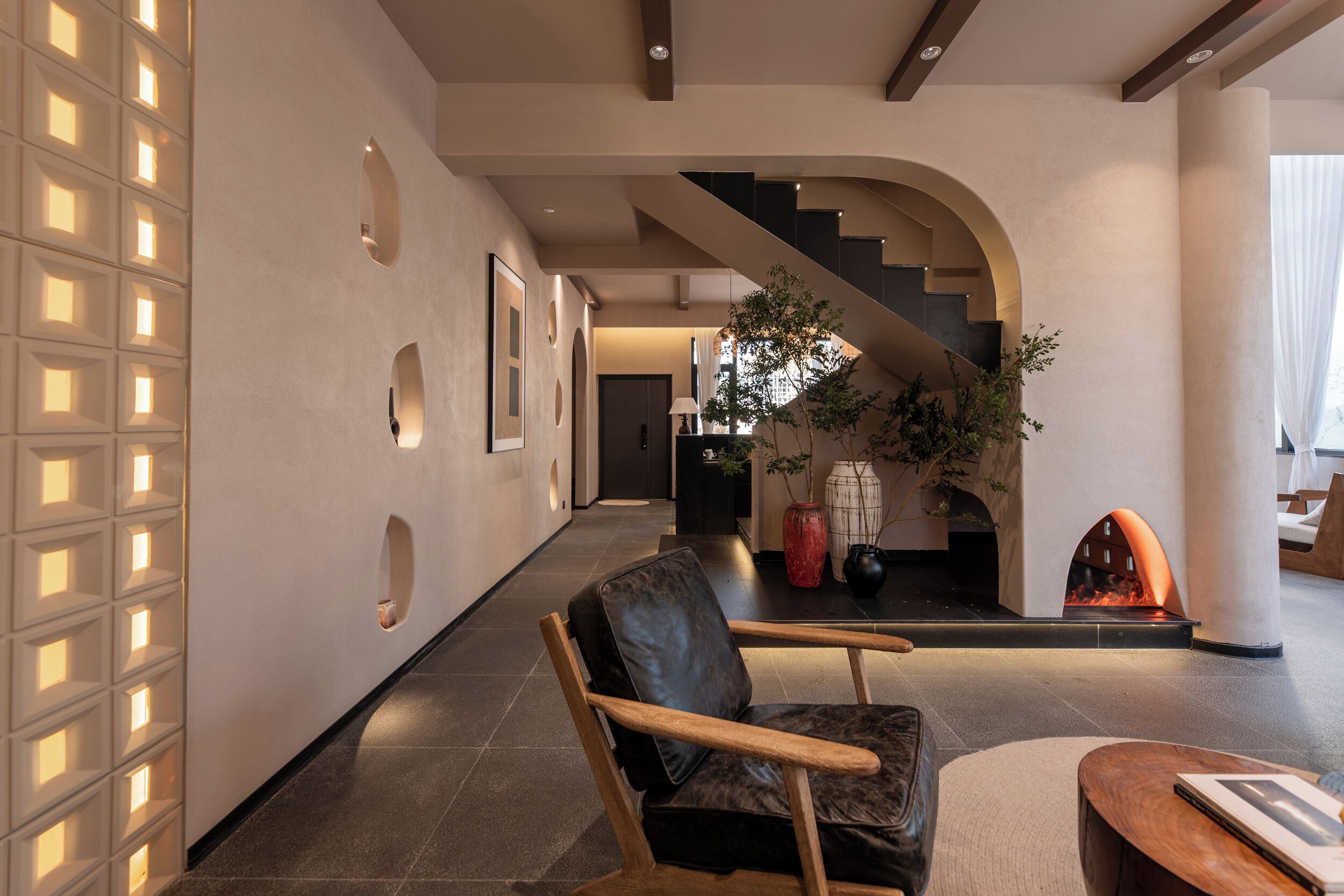 A modern interior with a staircase, a fireplace, and a seating area.