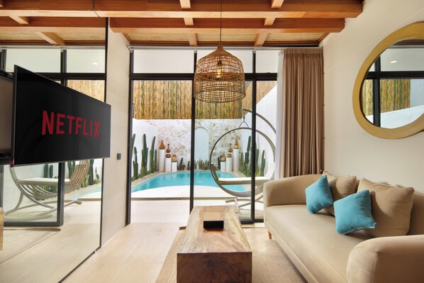Relax in this stylish living room with a large flat-screen TV, comfortable sofa, and access to the outdoor pool area.
