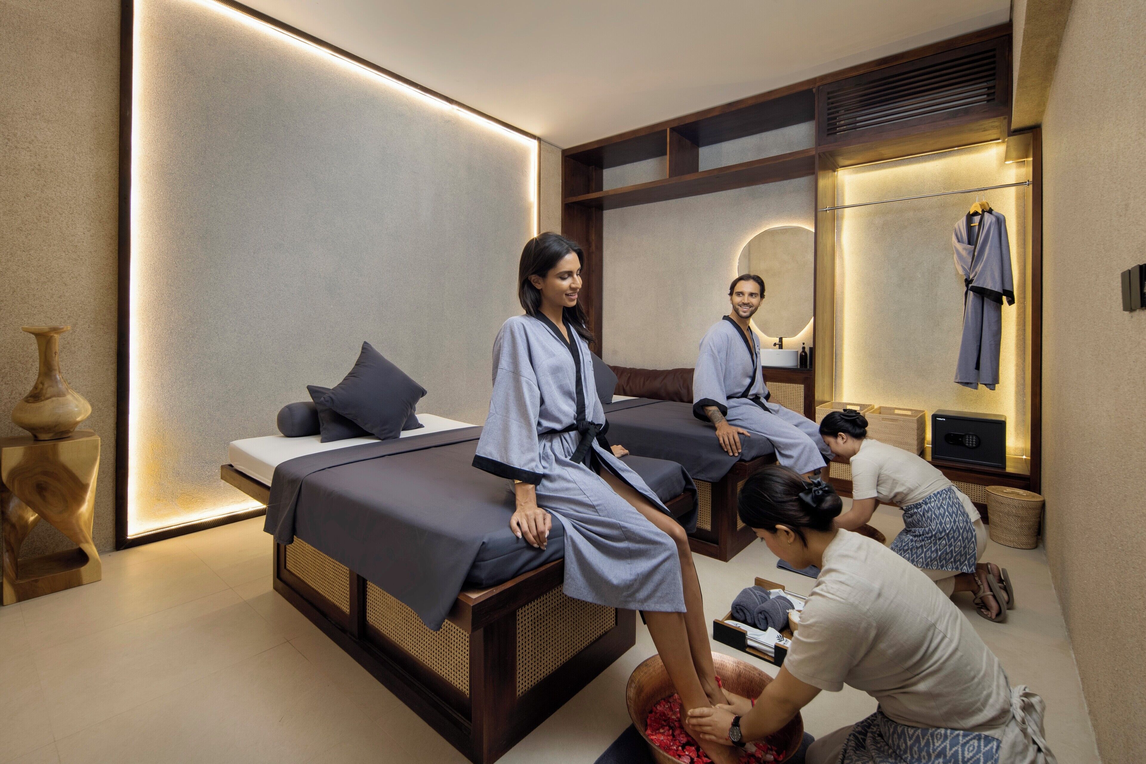 Een moderne spa-ruimte met een massagetafel, een grote spiegel en een bed met houten hoofdeinde.
