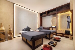 Un moderno spa con dos camillas de masaje, un espejo grande y un mueble de madera con toallas.