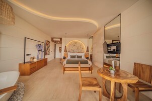 Una habitación de hotel moderna con una cama, un escritorio de madera, una mesa redonda y un espejo grande.