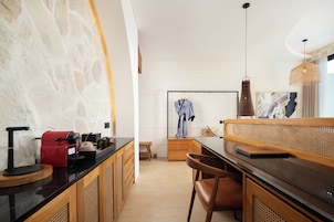 Una cocina moderna con encimera negra, armarios de madera, una cafetera roja y una bata colgada.