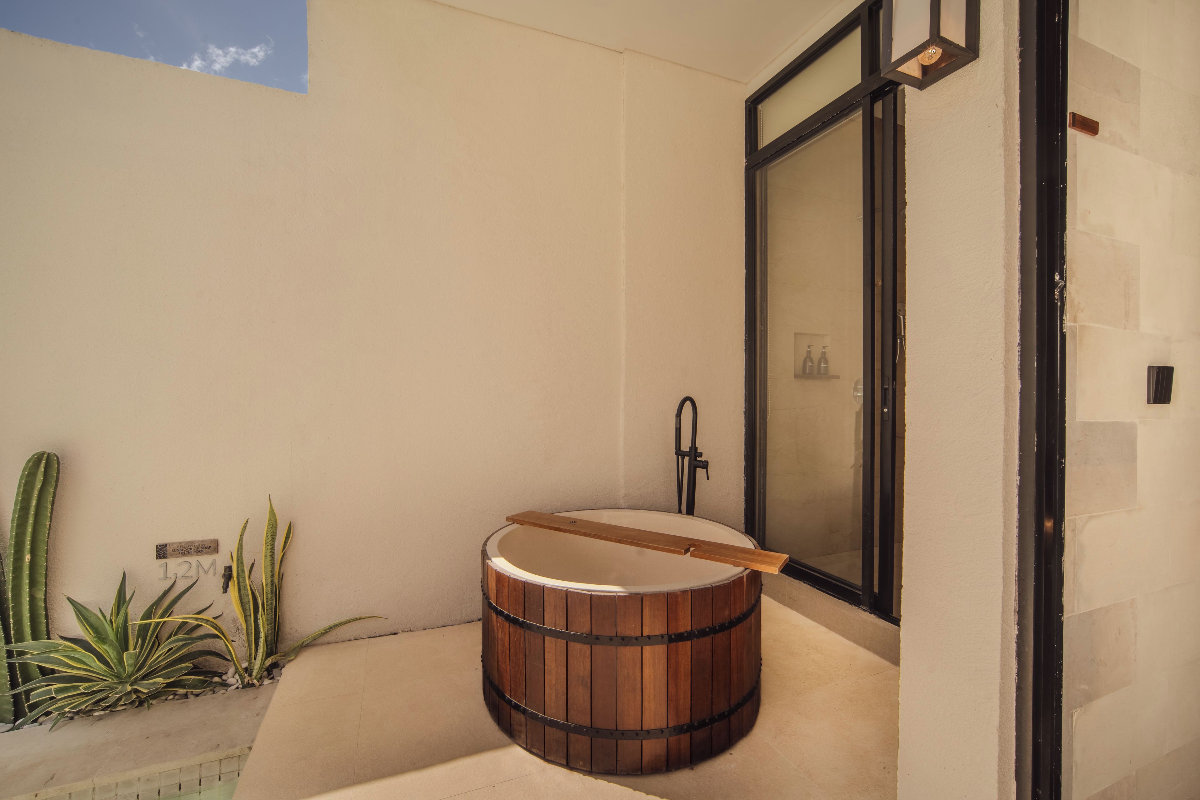 Un baño moderno con una bañera de madera, un lavamanos y una zona de ducha.