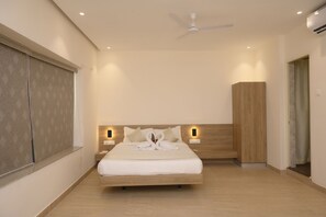 Un dormitorio moderno con una cama de madera, lámparas de noche, un ventilador de techo y un ventanal con persianas.