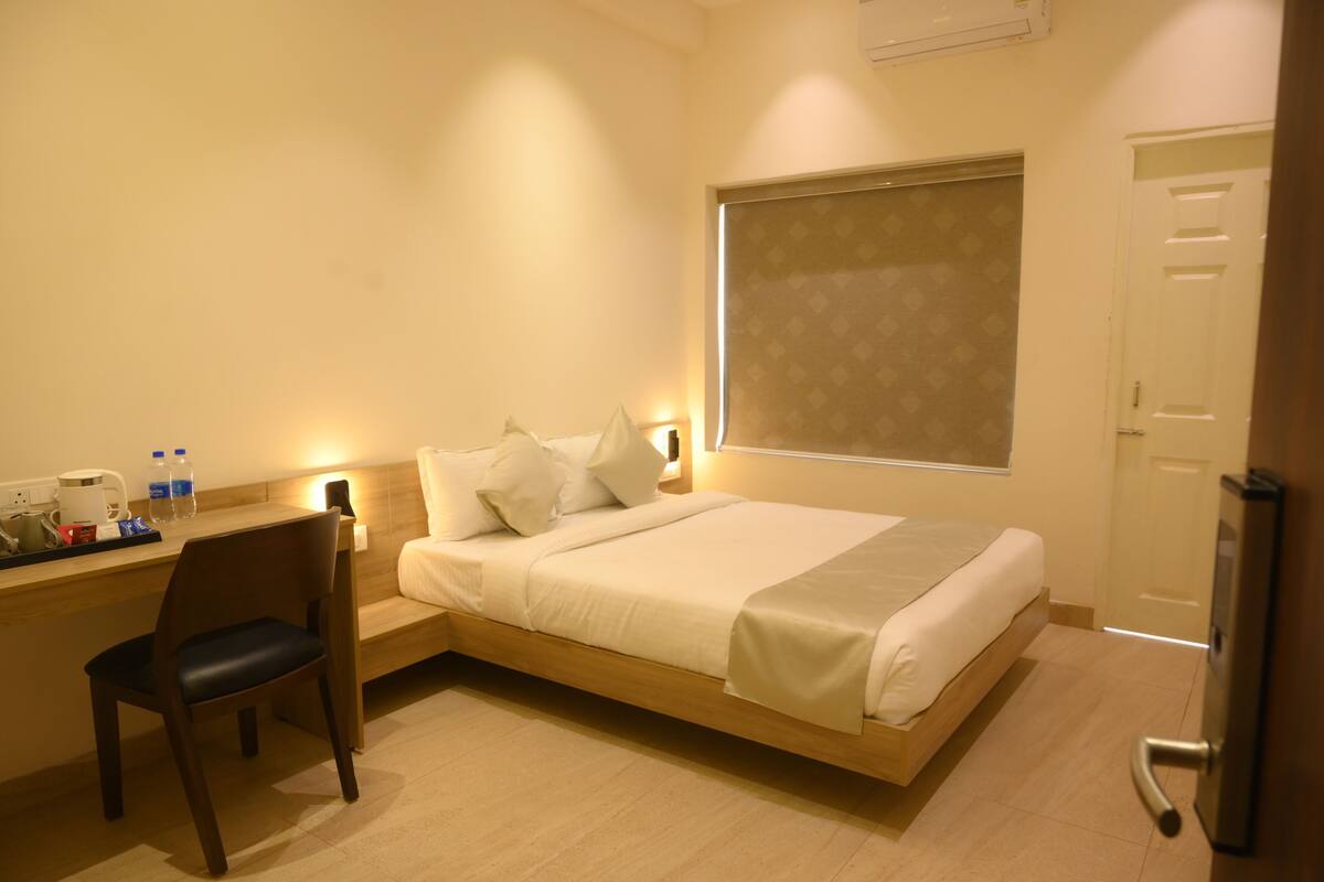 Una habitación de hotel con cama, escritorio, silla y ventana.