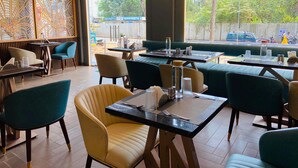 Un restaurante con mesas en el interior, vista a la calle y un separador decorativo.