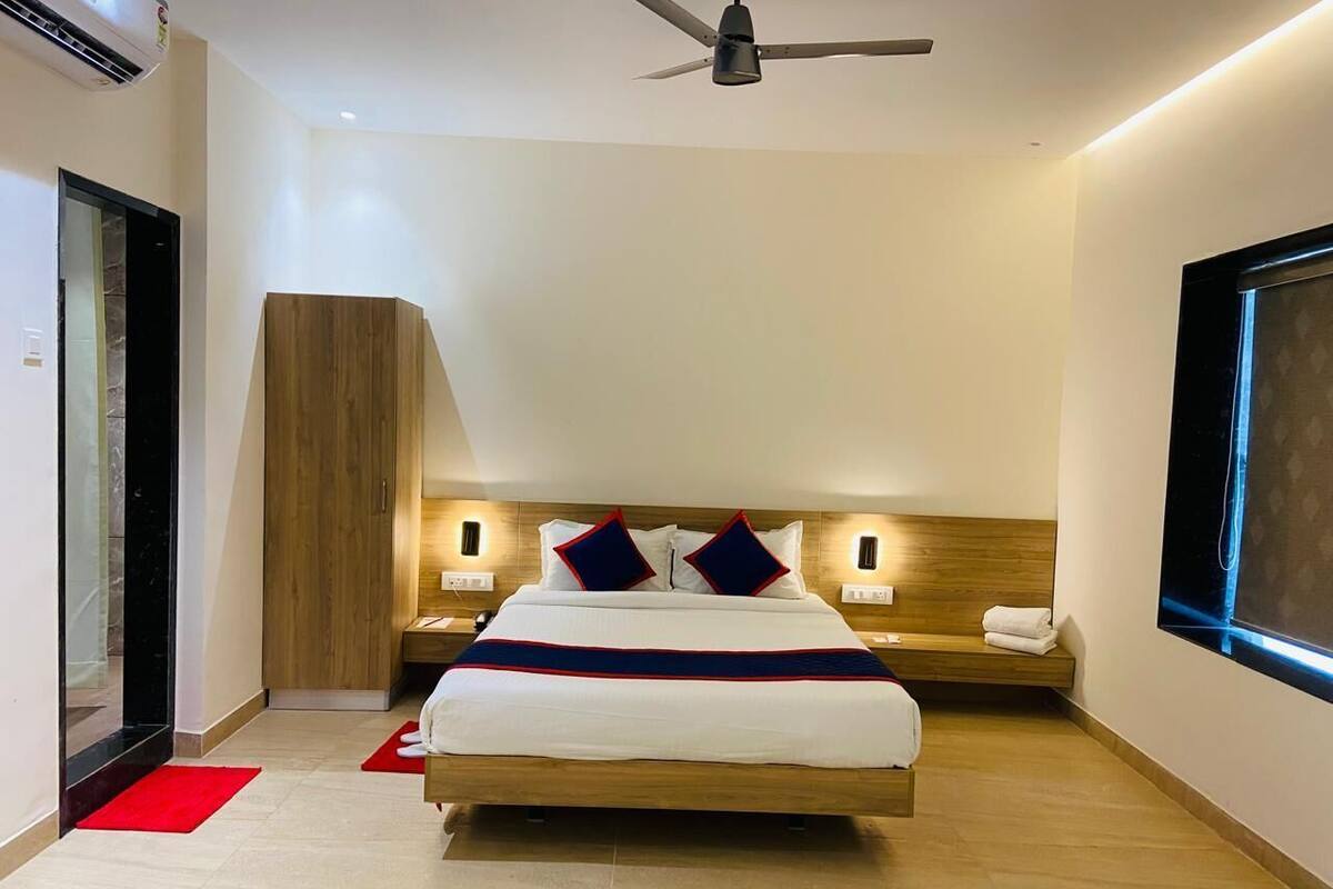 Una habitación de hotel moderna con una cama grande, cabecera de madera, mesitas de noche y un ventilador de techo.