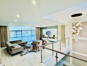 A spacious living area with a modern sofa, a coffee table, and a large window offering a view of the outdoors. - H & H Boutique and Spa (Roodepoort)