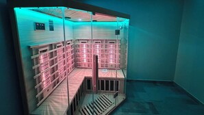 Uma sauna com bancos de madeira e paredes de vidro, iluminada por luzes azuis.