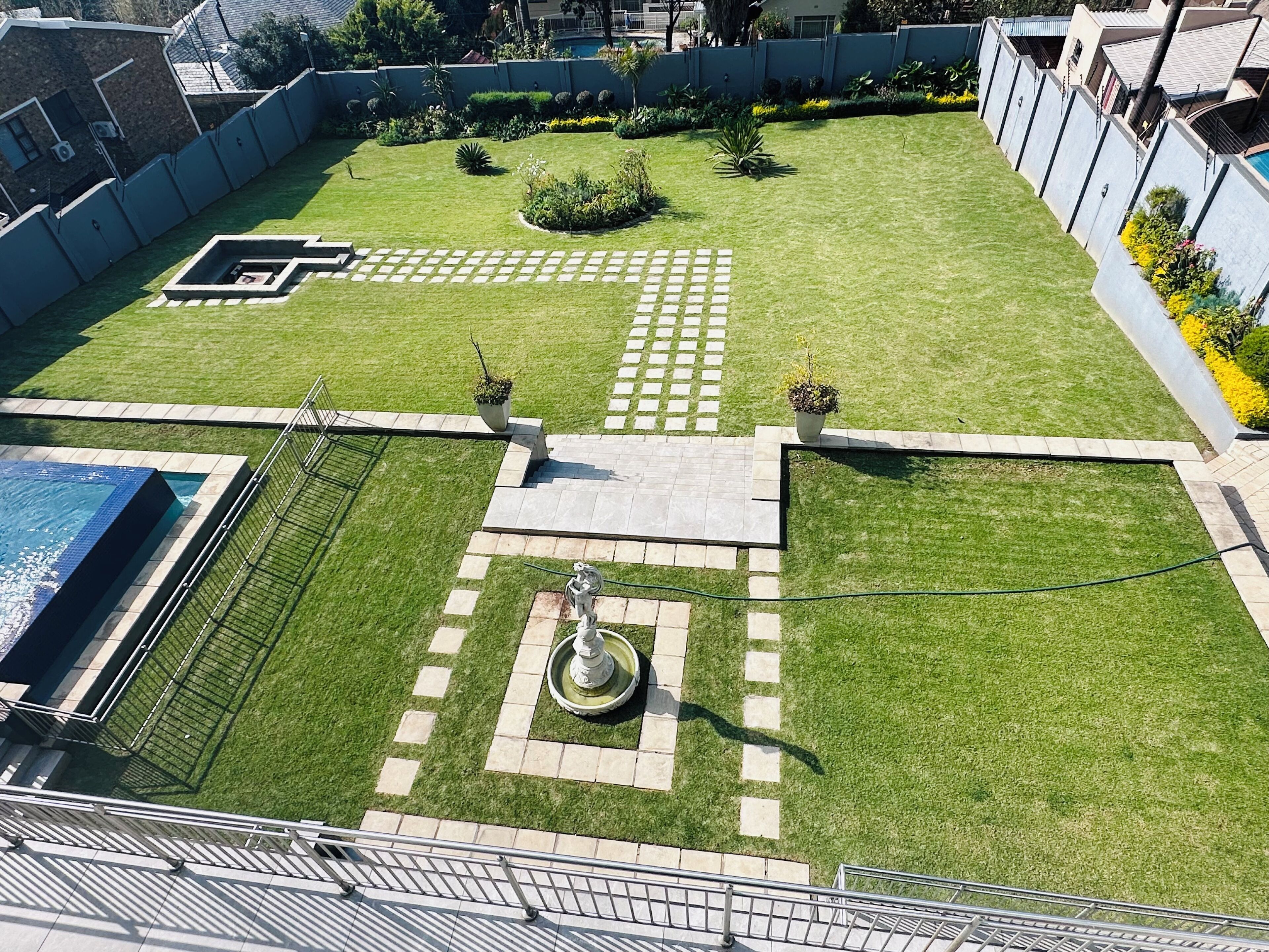 Un jardín en la azotea con piscina, una fuente y una estatua.
