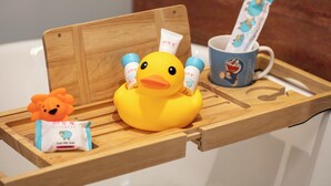 A wooden tray with a rubber duck, a small orange toy, and a packet of goat milk soup. - Wanda Yi Hotel Xi'an The Linow (Xi'an)