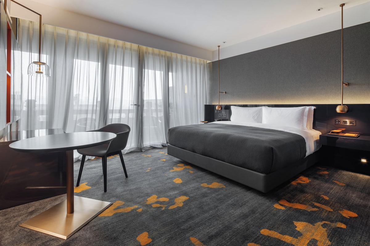 Una camera d'albergo moderna con un letto grande, una scrivania e una sedia.