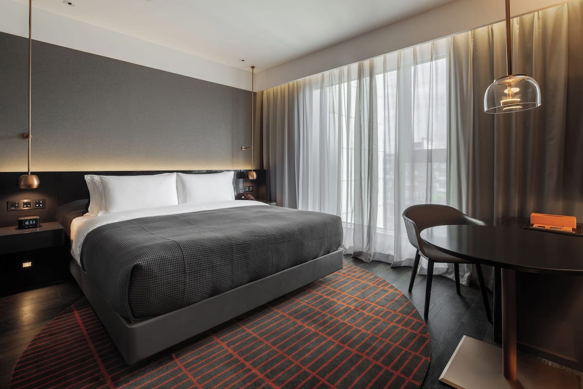 Una camera d'hotel moderna con un ampio letto, una scrivania e una sedia.