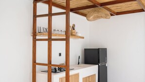 A modern kitchen with a wooden beam ceiling, a black refrigerator, and a white countertop. - Villa Kasih Satu (Gili Trawangan)