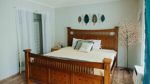 Ein Schlafzimmer mit einem hölzernen Bett, weißen Vorhängen, einem Nachttisch und einer Wanddekoration.