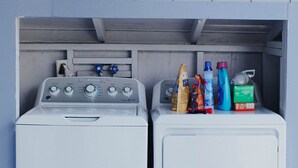 Zwei weiße Waschmaschinen mit einer Holzwand und einem Schild darüber mit der Aufschrift 'Laundry'.