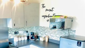 Een moderne keuken met witte kasten, een magnetron en een koelkast.