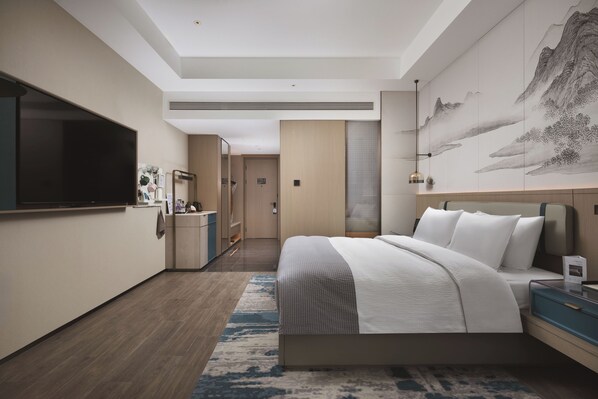 Een moderne hotelkamer met een groot bed, een flatscreen televisie, een bureau en een zichtbare badkamer door een open deur.