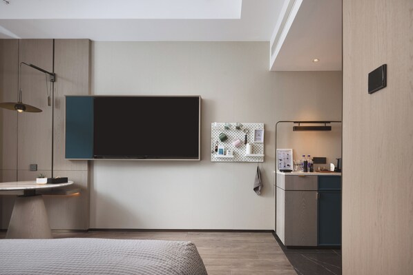 A modern bedroom with a bed, bedside table, and a large flat-screen TV mounted on the wall. - Wanda Moments - Yulin Yuyang (Yulin)
