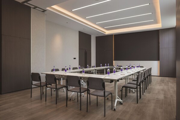 Una sala conferenze con un lungo tavolo, sedie, bottiglie d'acqua e una lavagna.