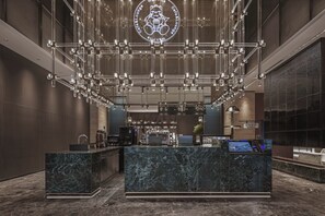 A modern hotel lobby with a marble reception desk, a digital check-in kiosk, and a large illuminated logo on the ceiling. - Wanda Moments - Yulin Yuyang (Yulin)