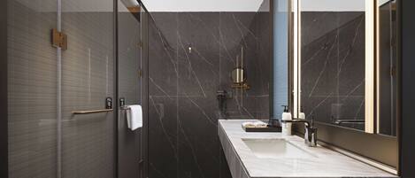Une salle de bain moderne avec une douche à parois de verre, un lavabo en marbre et un grand miroir.