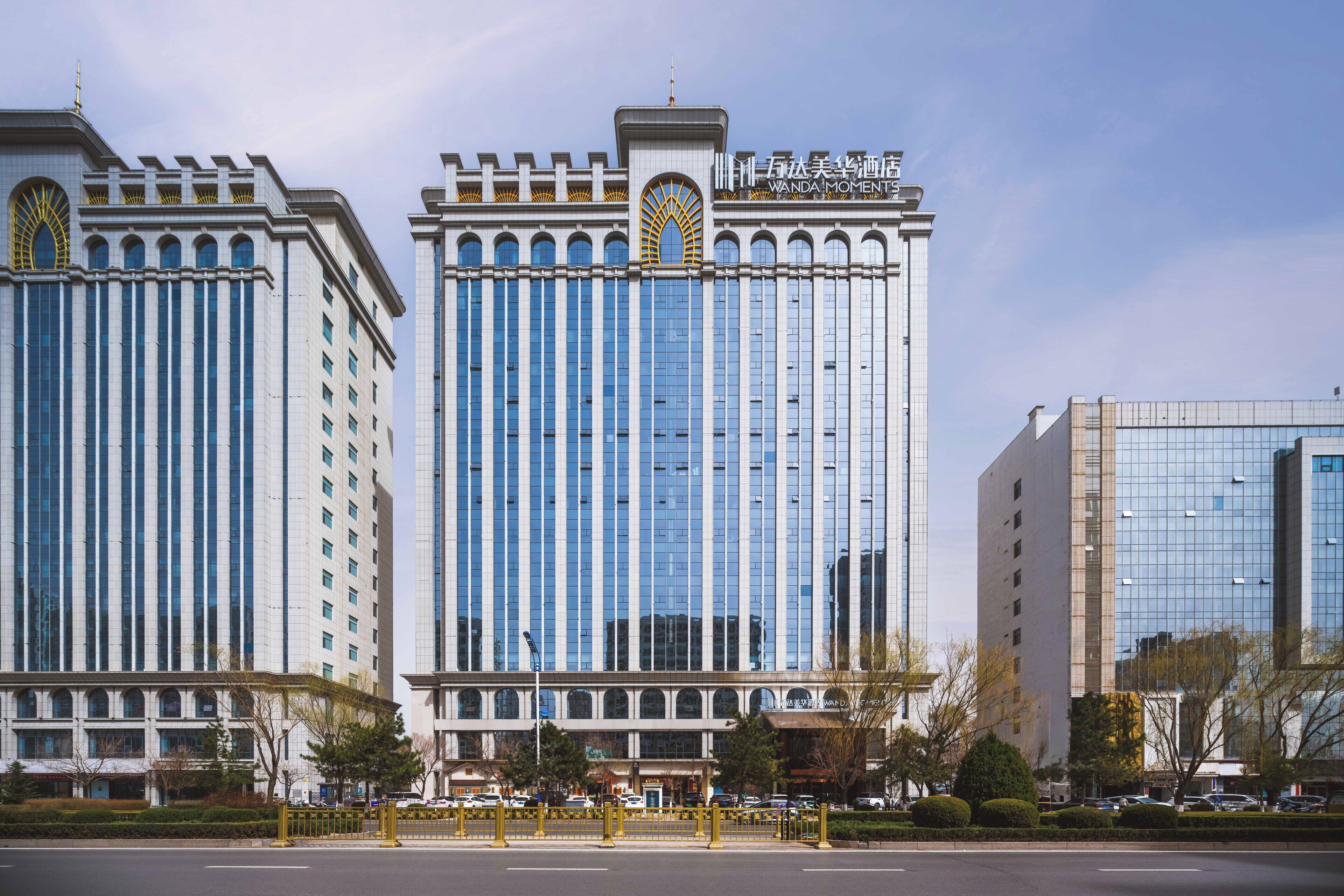 Un hotel moderno con una torre central y dos alas laterales, que presenta una fachada simétrica y grandes ventanales.