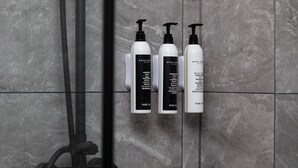A bathroom with three bottles of shampoo and conditioner on a tiled wall. - Wanda Yuehua Shanghai Wildlife Park (Shanghai)