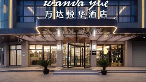 A hotel entrance with a revolving door, glass doors, and a sign above in both English and Chinese. - Wanda Yuehua Shanghai Wildlife Park (Shanghai)