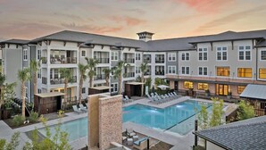 A multi-story hotel with a swimming pool, outdoor seating, and a landscaped courtyard.