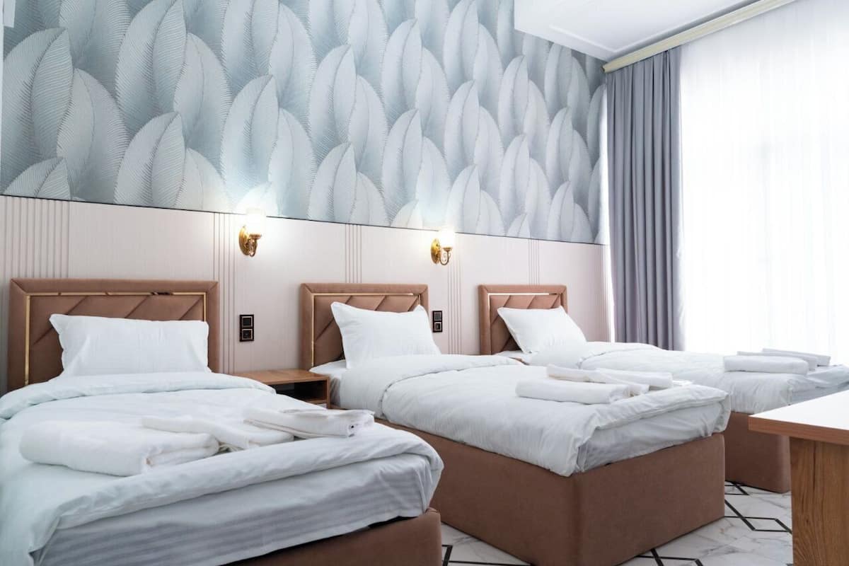 A hotel room with two beds, a large patterned wall, and a view of the outdoors.