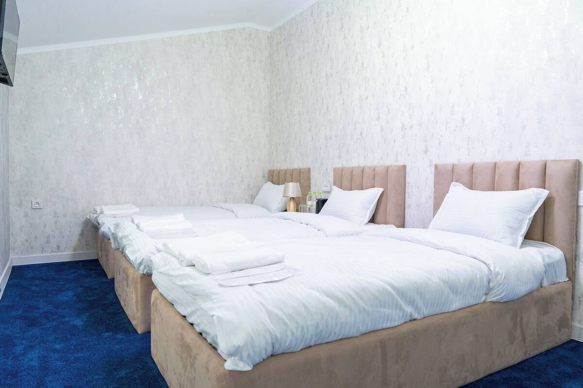 A hotel room with a large bed, a nightstand, and a lamp.
