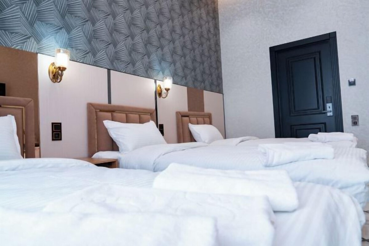 A hotel room with two beds, a large mirror, and a dark door.