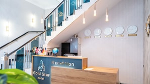 A hotel reception area with a wooden reception desk, a staircase, and clocks displaying times from various cities. - GOLD STAR PALACE HOTEL (Samarkand)