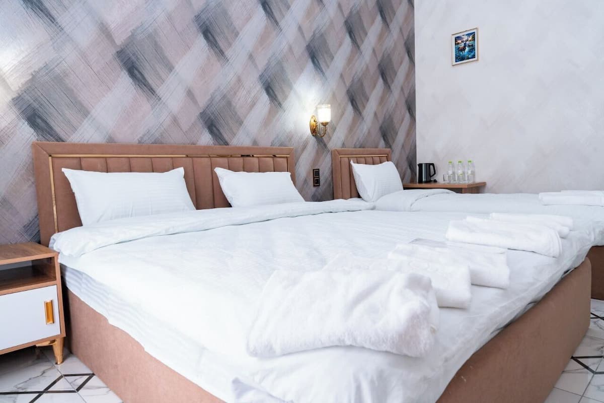 A hotel room with a large bed, two bedside tables, a wall-mounted light, and a picture on the wall.